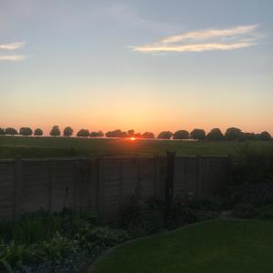 una puesta de sol sobre un campo con una valla en The Chalet, en Beverley
