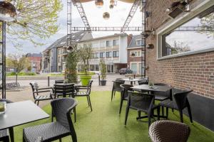 eine Terrasse mit Tischen und Stühlen und ein Gebäude in der Unterkunft Hotel De Boskar Pelt in Neerpelt