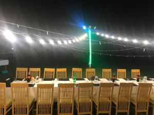 einem langen Tisch mit Stühlen und grünem Licht in der Unterkunft Mulberry Continental Hotel Skardu in Skardu