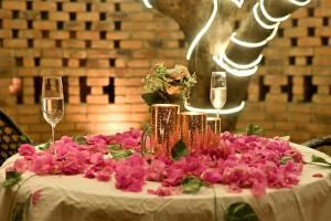 einen Tisch mit rosa Blumen und Gläsern Wein in der Unterkunft Saj By The Lake, Malshej Ghat in Malshej Ghat