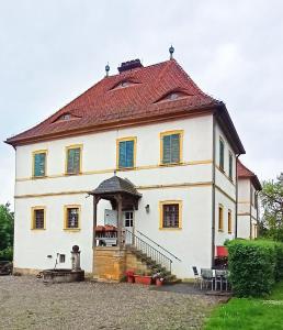 una gran casa blanca con techo rojo en Wohnung im Schlösschen, en Lichtenfels