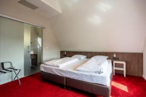 een slaapkamer met een groot bed en rode loper bij Hotel De Boskar Pelt in Overpelt