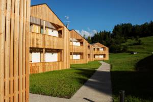 a wooden building with a fence next to a sidewalk at Chalet del Capriolo in Vodo Cadore