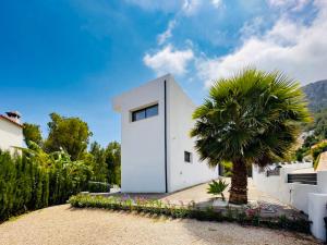 uma casa branca com uma palmeira em frente em Calpe villa lujo playa piscina jardin barbacoa ideal familias y grupos em Calpe