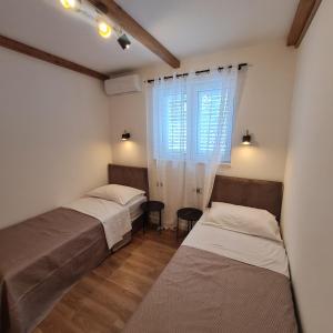 two beds in a room with a window at Apartment Mariniva in Kaštela