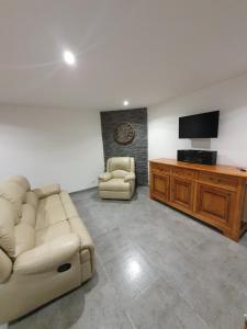 a living room with a couch and a flat screen tv at Gîte les 3 têtes de loups in Fumay