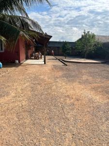 um pátio de terra com um edifício e uma palmeira em Casa mobiliada - Rondônia Rural Show em Ji-Paraná