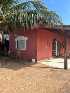 una casa roja con un gato sentado frente a ella en Casa mobiliada - Rondônia Rural Show en Ji-Paraná