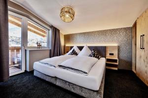 a bedroom with a large white bed and a window at Deluxe Apartment Zugspitze Ehrwald mit Pool, Sauna, direkt am Golfplatz in Ehrwald +16 photos