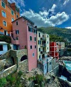 a pink building on a cliff next to a body of water at L'Incanto Divino 011024-LT-0023 in Riomaggiore