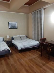 Un dormitorio con dos camas y una mesa y una ventana. en ERSI Apartaments, en Pogradec