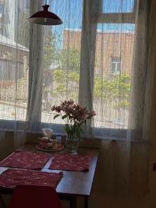 uma mesa com flores na frente de uma janela em Nina’s Sweet Home em Tbilisi