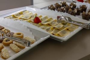 two trays of cookies and other desserts on a counter at Hotel Continental in Caorle