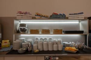 a kitchen with a shelf with cups and plates at Hotel Continental in Caorle