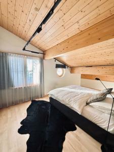 Schlafzimmer mit einem Bett mit Holzdecke in der Unterkunft Chalet Gütsch Andermatt in Andermatt