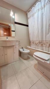 a bathroom with a toilet and a sink and a tub at Apartamento Playa de Daimuz in Daimuz