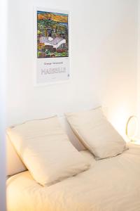 łóżko z 2 poduszkami i plakatem na ścianie w obiekcie Appartement au coeur du Vieux-Port w Marsylii