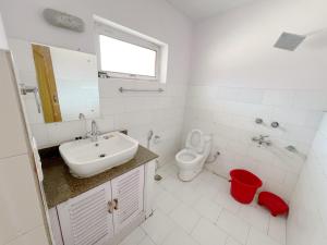 a white bathroom with a sink and a toilet at Hotel Lumbini in Leh