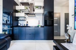 a kitchen with blue cabinets and a black counter at Luxury Apartment With Spa Bath- City Centre, Free Parking by StayNest in Rzeszów