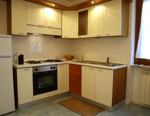 una cucina con armadi bianchi, piano cottura e lavandino di Gli Ulivi Apartment a Capaccio-Paestum