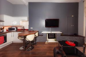 cocina con mesa y TV en la pared en Warm 1 Bed Apartment by Holyrood Palace and Park!, en Edimburgo