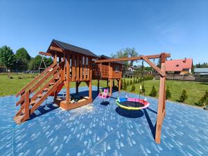 ein hölzerner Spielplatz mit einer Schaukel auf dem Wasser in der Unterkunft MaGórka in Krempna