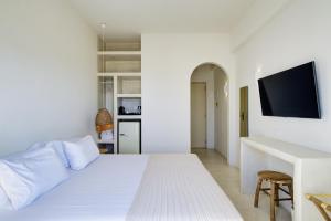 a white bedroom with a white bed and a desk at KOKOON in Parikia