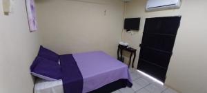 a small bedroom with a purple bed and a door at Hostal San José in La Unión