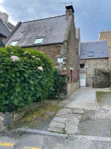 an old stone house with a hedge and a white door at le 2018 in Cancale