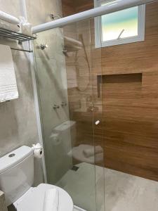 a bathroom with a toilet and a glass shower at Pousada Thermas das Montanhas in Águas de Lindoia
