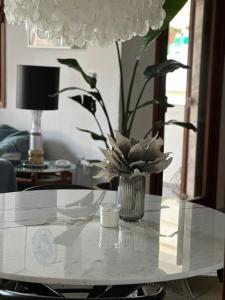 a white table with a vase of flowers on it at Nice, spacious and bright apartment in Thermi, Thessaloniki. in Thérmi