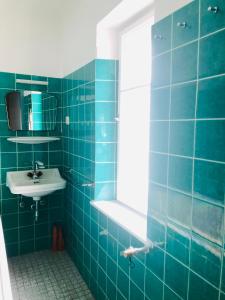 bagno piastrellato blu con lavandino e specchio di Holmes Café & Pension a Engelhartszell