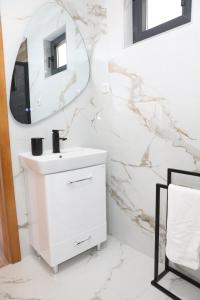 a white bathroom with a sink and a mirror at Bungalov La Repit in Šipovo