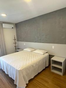 アグアス・デ・リンドイアにあるPousada Thermas das Montanhasの白いベッドと灰色の壁が備わるベッドルーム1室が備わります。