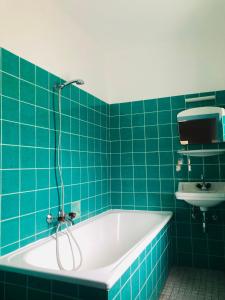 a blue tiled bathroom with a tub and a sink at Holmes Café & Pension in Engelhartszell