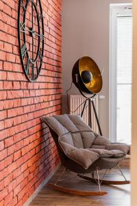 a brick wall with a chair and a clock at LIKE APARTMENT in Kołobrzeg +43 photos