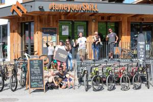 um grupo de pessoas em pé em frente a um edifício com bicicletas em SKILL Mountain Lodge - Ski und Bike Hostel inklusive JOKER CARD em Saalbach Hinterglemm