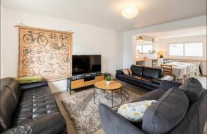sala de estar con sofás de cuero negro y TV en La villa Hérault en Cholet