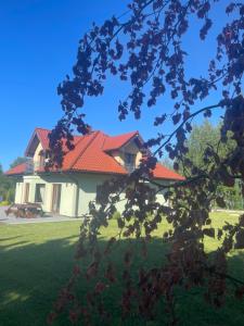 uma casa com um telhado vermelho num jardim verde em Pogodna Zagroda-Dom na Kaszubach & Strefa Spa em Kościerzyna
