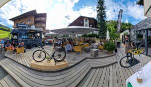 una bicicleta estacionada en una terraza de madera junto a un restaurante en SKILL Mountain Lodge - Ski und Bike Hostel inklusive JOKER CARD, en Saalbach Hinterglemm