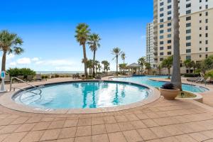 a large swimming pool with palm trees and a building at Indigo East 1004 in Perdido Key