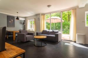 a living room with a couch and chairs and a table at Hoefbos bungalow in Otterlo