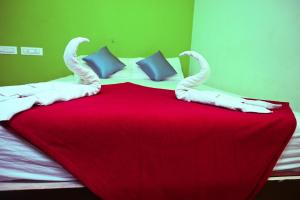 a bed with a red and white blanket and pillows at Royal Rock INN in Harihar