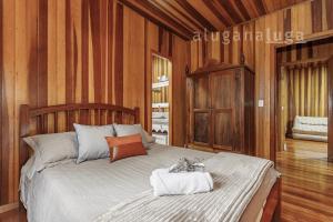 een slaapkamer met een groot bed en houten wanden bij Colina das Araucárias Natureza Família Serra in Florianópolis