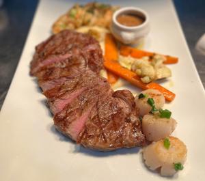 a white plate with steak and vegetables and sauce at La Sapinette in Val-David