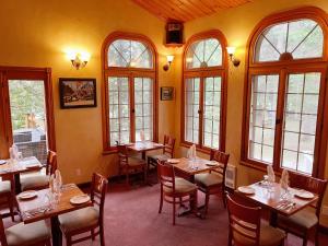a dining room with tables and chairs and windows at La Sapinette in Val-David