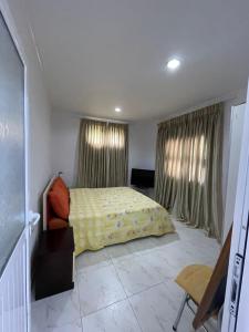 ein Schlafzimmer mit einem Bett und zwei Fenstern mit Vorhängen in der Unterkunft Isufi House in Delvinë