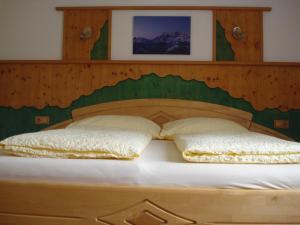a bed with a wooden headboard and two pillows at Appartement Ahornegger in Schladming