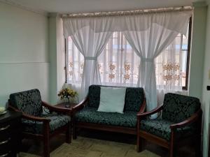una habitación con 2 sillas y una ventana con cortinas en Habitaciones en Edificio Ginebra Manizales en La Linda