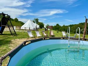 a swimming pool with chairs and a tent at Glamping Bieszczady z basenem in Solina